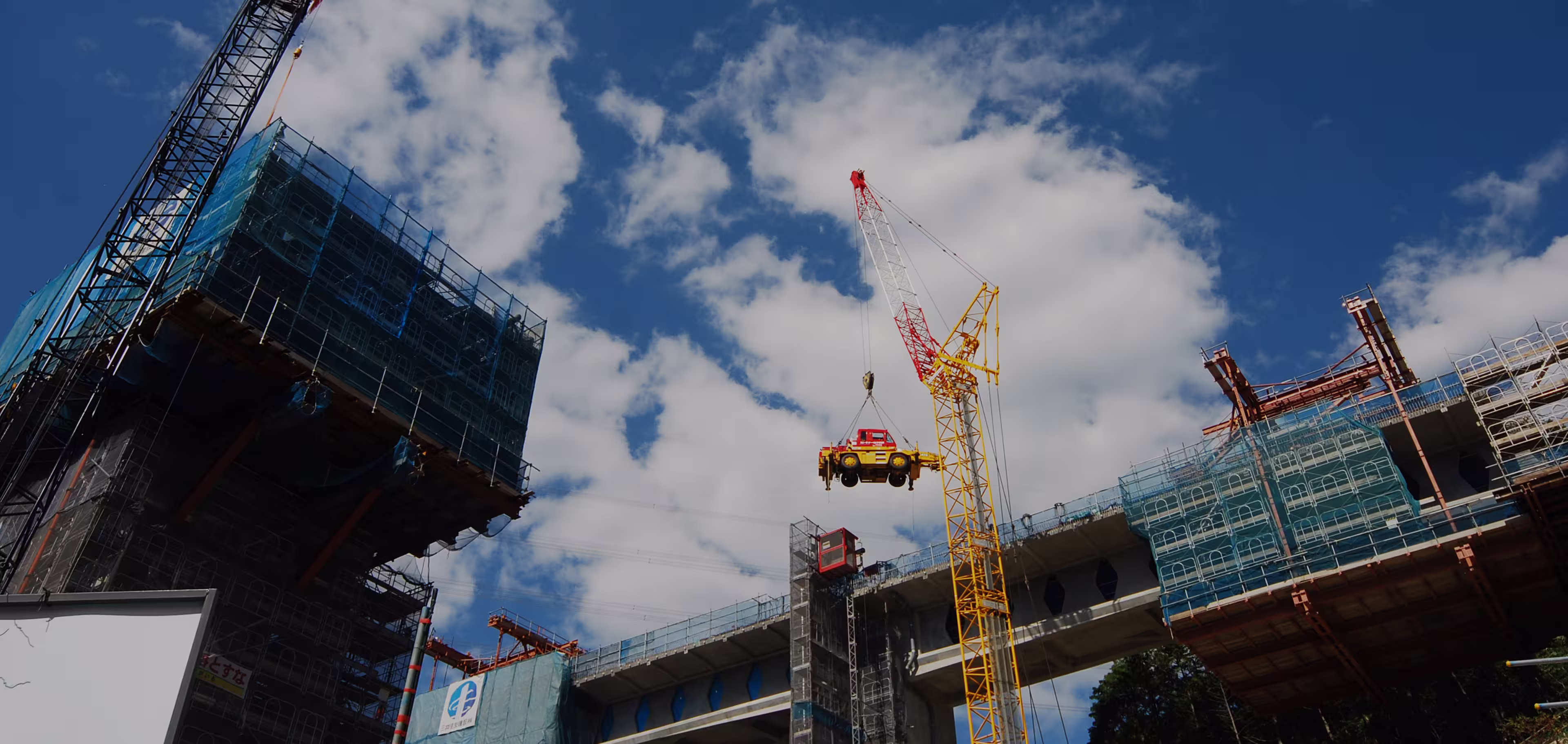 大型クレーンがガラス張りの建物前で稼働している写真